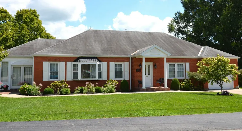Single-story red brick house with white trim, a front porch and a green lawn